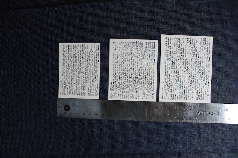 Pu&ograve; includere: Tre carte bianche con testo nero su uno sfondo di tessuto blu scuro. Le carte sono allineate orizzontalmente e misurano circa 5 cm di larghezza e 7,5 cm di altezza. Un righello &egrave; posizionato sotto le carte.