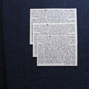 Pu&ograve; includere: Tre carte bianche con testo ebraico stampato in inchiostro blu. Il testo &egrave; in un carattere ebraico tradizionale e include le parole "Shema Yisrael" e "Adonai Eloheinu Adonai Echad".