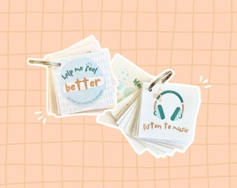 Op de afbeelding: Twee kleine, witte, kaartvormige boekjes met sleutelringen. Het eerste boekje heeft een blauwe cirkel met de tekst "Help me feel better" en de tekst "On-the-go coping strategies". Het tweede boekje heeft een groene illustratie van een koptelefoon met een noot en de tekst "Listen to music".