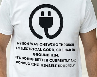 Puede incluir: Camiseta blanca con un símbolo de toma de corriente negro y el texto "MY SON WAS CHEWING THROUGH AN ELECTRICAL CORD, SO I HAD TO GROUND HIM. HE'S DOING BETTER CURRENTLY AND CONDUCTING HIMSELF PROPERLY."