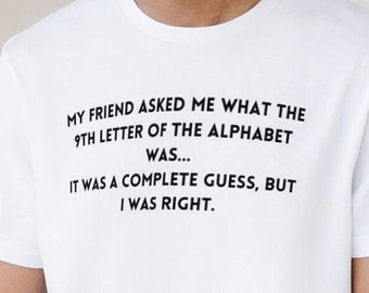 Puede incluir: Camiseta blanca con texto negro: "MI AMIGO ME PREGUNTÓ CUÁL ERA LA 9ª LETRA DEL ALFABETO... FUE UNA COMPLETA SUPOSICIÓN, PERO TENÍA RAZÓN". La camiseta se lleva con vaqueros negros y un reloj negro. La persona tiene barba.