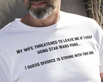 Puede incluir: Una camiseta blanca con un mensaje humorístico sobre los juegos de palabras de Star Wars. El texto dice: "Mi esposa amenazó con dejarme si sigo usando juegos de palabras de Star Wars... Supongo que el divorcio es fuerte con este."