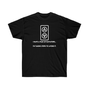May include: Black t-shirt with a white graphic of a lift button panel with up and down arrows. The text "I have a fear of elevators... I'm taking steps to avoid it." is printed below the graphic.
