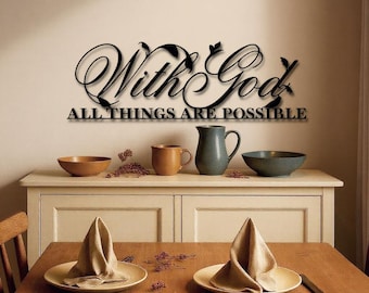 Może przedstawiać: Czarna metalowa dekoracja ścienna z napisem "With God All Things Are Possible" w eleganckim skrypcie. Sztuka jest wyświetlana nad kremową szafką z różnymi artykułami kuchennymi, w tym miskami, kubkami i dzbankiem. Drewniany stół jest nakryty talerzami i serwetkami.