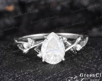 May include: A pear-shaped diamond engagement ring with a delicate, leaf-shaped band. The ring is set in silver and features a pear-shaped diamond.