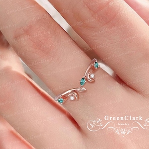 May include: A delicate rose gold ring with a crescent moon and star design. The ring is adorned with small green gemstones.