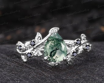 May include: A pear-shaped green agate ring set in silver with black diamond accents. The ring features a delicate vine design with leaves and branches.