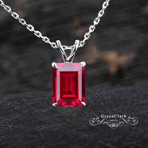 May include: A silver chain necklace with a pendant featuring a large, emerald-cut ruby gemstone.