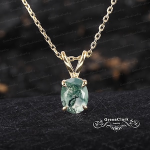May include: A gold chain necklace with a pendant featuring a green moss agate gemstone. The gemstone is oval-shaped and has a unique, natural pattern.