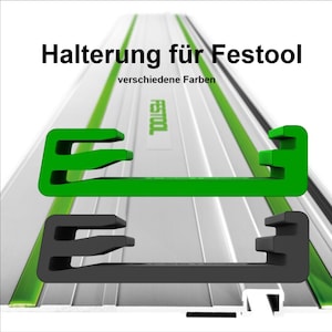 Op de afbeelding: Groene en zwarte kunststof geleiderailklemmen voor een Festool-zaag. De tekst "Halterung für Festool" en "verschiedene Farben" is zichtbaar op de afbeelding.