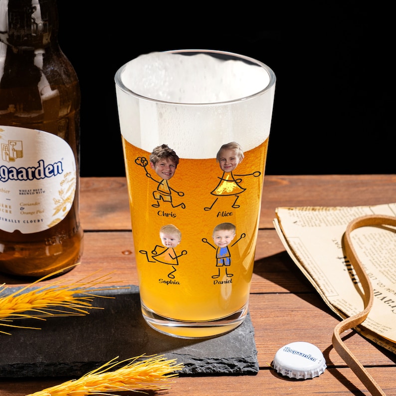 May include: A tall clear glass beer mug with a yellow beverage inside. The mug has a personalized design with stick figure drawings of four people with their faces in the drawings. The names Chris, Alice, Sophia, and Daniel are written below the figures.
