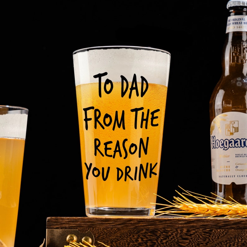 May include: A clear glass beer mug with the text "To Dad From The Reason You Drink" printed on the side. The mug is filled with a light yellow liquid.