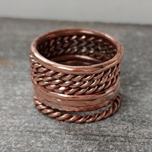 May include: A copper ring with a braided design. The ring is made of multiple bands of copper wire that are woven together.