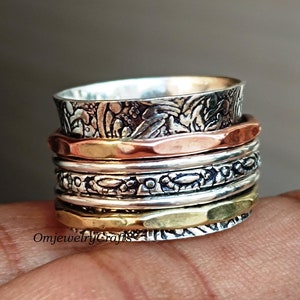 May include: A silver, copper, and gold spinning ring with intricate designs. The ring is made of multiple bands that spin freely around each other.