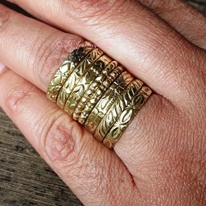 May include: A stack of seven gold-toned rings with intricate floral designs and textured surfaces.