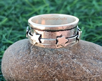 May include: A silver spinning ring with a textured band and five star cutouts. The ring is engraved with the text "OmjewelryCrafts".