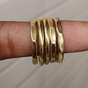 Könnte beinhalten: Fünf goldene Ringe, die übereinander gestapelt sind. Die Ringe sind strukturiert und haben eine gehämmerte Oberfläche.