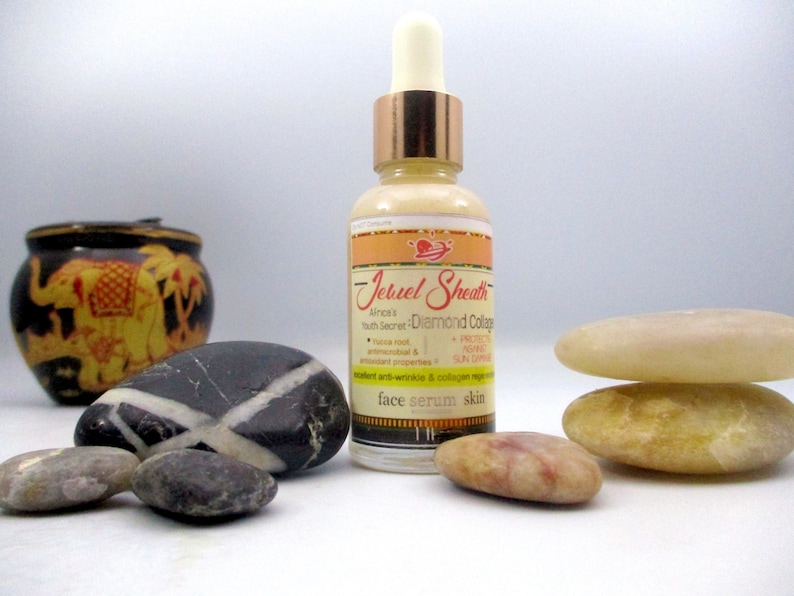 May include: A clear glass bottle with a gold cap and a label that reads "Jeruel Sheath Aince's Youth Secret Diamond Collagen". The bottle is sitting on a white surface with several smooth stones.