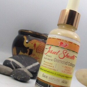 May include: A clear glass bottle with a gold lid and a label that reads "Jewel Sheath Africa's Youth Secret: Diamond Collagen". The label also includes the text "Yucca root, antimicrobial & antioxidant properties, protects against sun damage, talent anti-wrinkle & collagen regeneration, face serum skin".