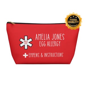 May include: A red medical alert pouch with a gold zipper. The pouch features the text "AMELIA JONES EGG ALLERGY" and "EPIPENS & INSTRUCTIONS". A medical alert symbol is on the left side. A "Premium Quality" seal is in the upper right corner.