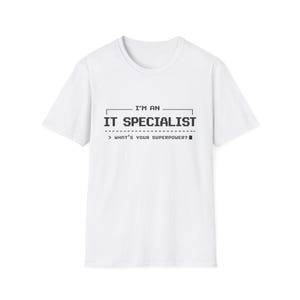 May include: White t-shirt with the text "I'M AN IT SPECIALIST" in black, along with the question "WHAT'S YOUR SUPERPOWER?" in a pixelated font. The shirt is a crew neck style.