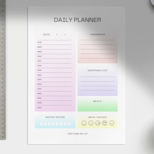 Könnte beinhalten: Ein druckbarer Tagesplaner mit Abschnitten für Erinnerungen, eine Einkaufsliste, Mahlzeiten, Wasseraufnahme und einen Stimmungs-Tracker. Der Planer hat ein pastellfarbenes Farbschema und den Text "You can do it!" am unteren Rand.
