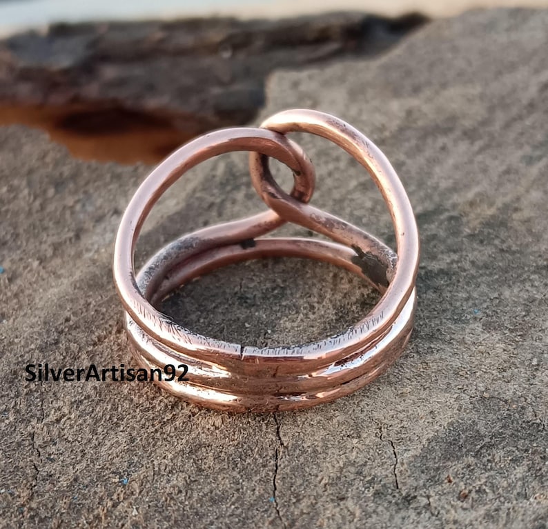 Puede incluir: Un anillo de cobre con un dise&ntilde;o trenzado. El anillo est&aacute; hecho de tres hilos de alambre que se trenzan para formar una forma &uacute;nica.