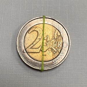 Może przedstawiać: Srebrna i złota moneta dwueurowa z flagą Unii Europejskiej i napisem "2 EURO" na awersie.