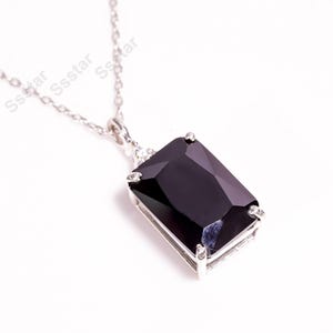 May include: A silver chain necklace with a black gemstone pendant. The gemstone is a rectangular cut and has a faceted design.