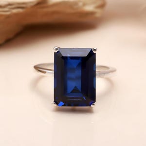 Op de afbeelding: Een zilveren ring met een grote, donkerblauwe, smaragd geslepen edelsteen.