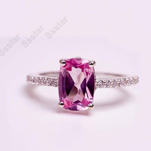Peut inclure: Une bague en argent avec une pierre précieuse rose et une bande de petites pierres claires.