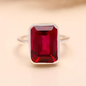 Peut inclure: Une bague en argent avec une grande pierre précieuse rouge foncé de taille émeraude.