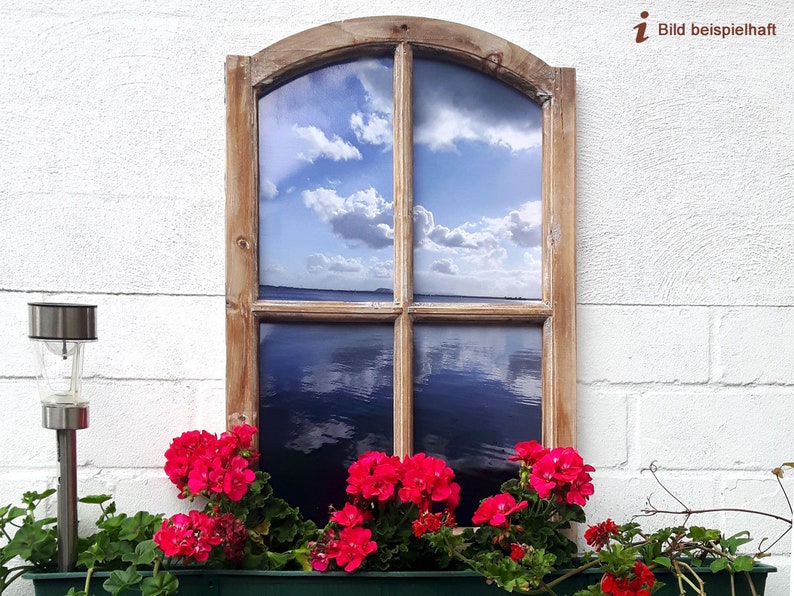 May include: A rustic wooden window frame with a view of a blue sky and water. Bright red flowers in a green planter box sit below the window. A solar-powered lamp is to the left of the window.