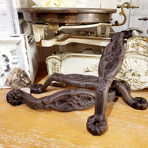 Peut inclure: Deux poignées de porte en fonte ornées, de couleur brun foncé, avec des motifs floraux complexes. Les poignées sont sur une surface en bois.