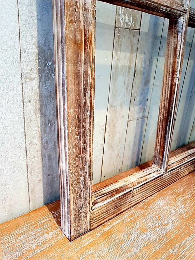 May include: A rustic, rectangular wooden frame with a distressed finish. The frame is made of light brown wood with visible grain and white paint accents. The frame is set against a light blue and white wooden background.