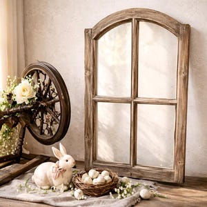 May include: A rustic wooden spinning wheel adorned with white roses and greenery, alongside a white bunny with a pink bow, a nest of eggs, and a weathered wooden window frame. The scene evokes a vintage, farmhouse aesthetic.