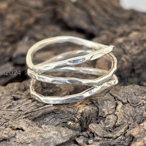 Könnte beinhalten: Silberring mit gehämmerter Oberfläche. Der Ring besteht aus drei miteinander verdrehten Bändern.