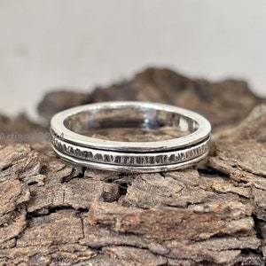 May include: A silver ring with a textured band. The ring is simple and elegant, and would make a great gift for a special occasion.