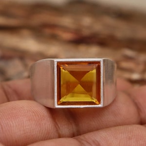 Peut inclure: Une bague en argent avec une pierre précieuse jaune de forme carrée sertie au centre.