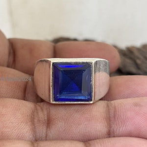 Könnte beinhalten: Ein silberner Ring mit einem quadratischen blauen Edelstein.