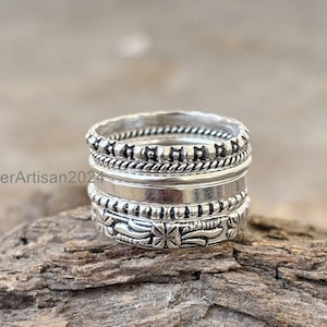 May include: A silver ring set with four bands, each with a different textured design. The bands are stacked on top of each other, creating a unique and stylish look.