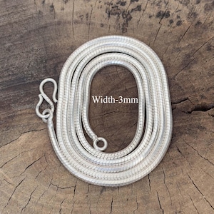 Op de afbeelding: Een zilverkleurige ketting met een slangenkettingontwerp, 3 mm breed, wordt getoond op een houten oppervlak. De ketting heeft een haaksluiting. De tekst "Width-3mm" is zichtbaar.