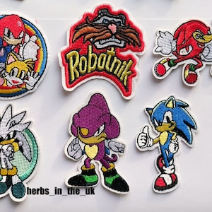 May include: Set of 10 embroidered iron-on patches featuring characters from the Sonic the Hedgehog video game series. The patches include Sonic, Tails, Knuckles, Robotnik, and Shadow. The patches are all in different colours and have a variety of designs.