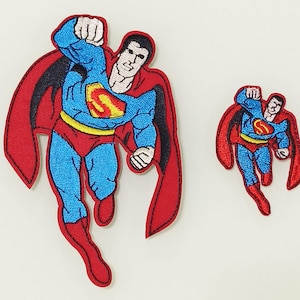 May include: Two embroidered iron-on patches of Superman flying. The larger patch is red, blue, and black. The smaller patch is red, blue, and yellow.