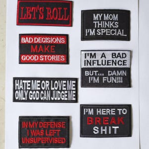 以下が含まれることがあります： さまざまな言葉が書かれた、白黒の刺繍入りアイロン接着パッチ8枚。パッチには白、赤、グレーの文字が使用されています。言葉には、「Let's Roll」、「Bad Decisions Make Good Stories」、「My Mom Thinks I'm Special」、「I'm A Bad Influence But... Damn I'm Fun!!!」、「Hate Me Or Love Me Only God Can Judge Me」、「I'm Here To Break Shit」、「In My Defence I Was Left Unsupervised」などがあります。