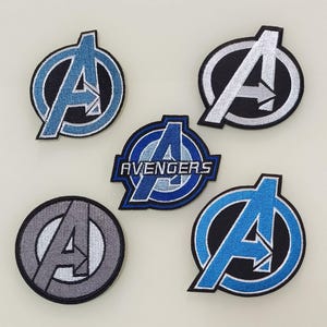 以下が含まれることがあります： アベンジャーズのロゴが刺繍されたアイロン接着パッチが5つ。ロゴはスタイリッシュな「A」で、右を向いた矢印が付いています。パッチは、青、グレー、白など、さまざまな色があります。