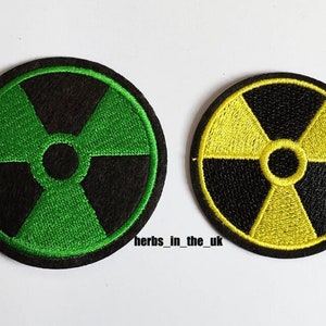 May include: Two embroidered iron-on patches featuring a black and green radiation symbol and a black and yellow radiation symbol.