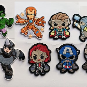 Peut inclure: Ensemble de 10 patchs brodés thermocollants représentant divers personnages de super-héros, dont Hulk, Iron Man, Doctor Strange, Thor, Captain America et Black Panther. Les patchs sont colorés et détaillés, dans un style cartoon.