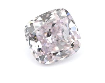 May include: A cushion-cut diamond with a soft pink hue. The gemstone has multiple facets that reflect light, creating a sparkling effect. The diamond is set against a white background.