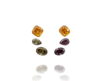 May include: An assortment of loose gemstones in various shapes and colors. Two square-cut, orange-yellow gems are at the top, with a pear-shaped olive-green gem and an oval olive-green gem below. On the right, a pear-shaped purple gem and an oval purple gem are visible.